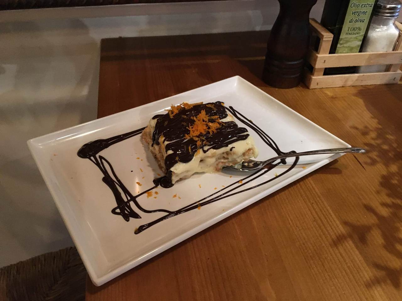 Tiramisu with orange zest and dark chocolate, beautifully arranged on a clean plate with a silver spoon.
