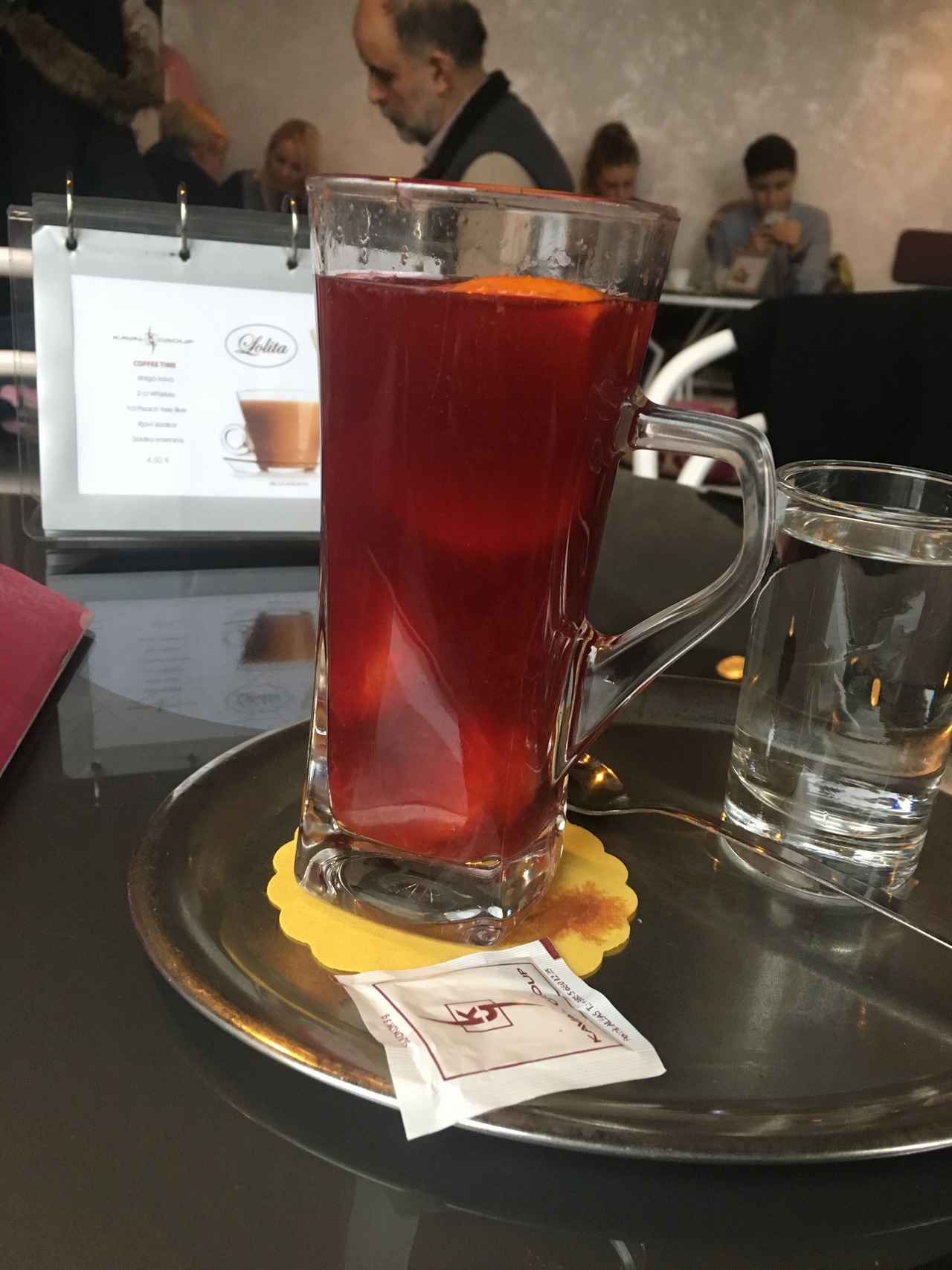 A tall glass filled with red punch. It has fruits swimming in the punch