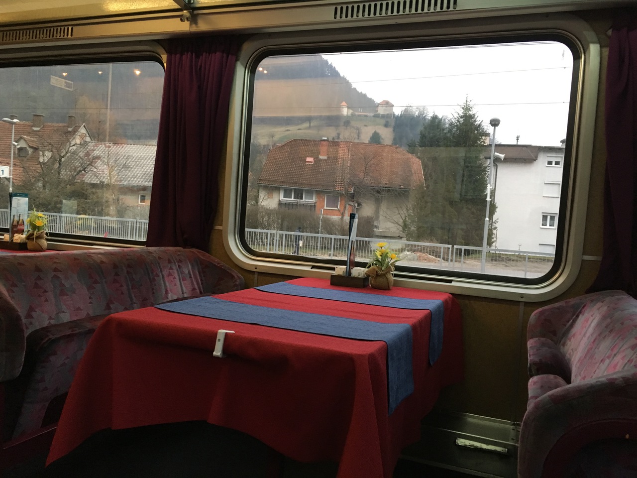 A wide open dining car with cozy benches the low backs of which offer a great view of the scenery through panorama windows